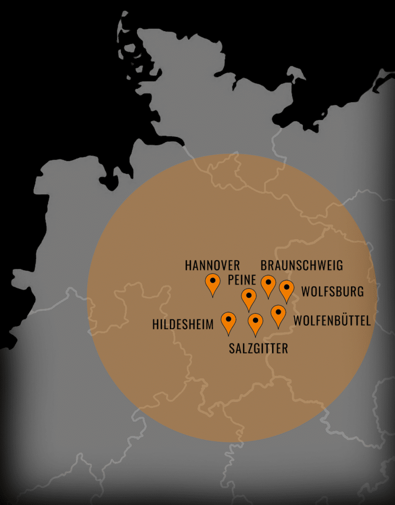 Auf einer Karte, die Mitteldeutschland hervorhebt, ist ein kreisförmiger Bereich mit Standortmarkierungen für Hannover, Peine, Braunschweig, Wolfsburg, Hildesheim, Salzgitter und Wolfenbüttel markiert. Besonders die Brandmeldeanlage in Wolfenbüttel sticht als wichtiger Punkt innerhalb des Kreises hervor.